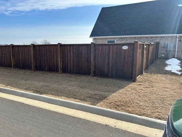 Dark-stained wood privacy fence along a residential street