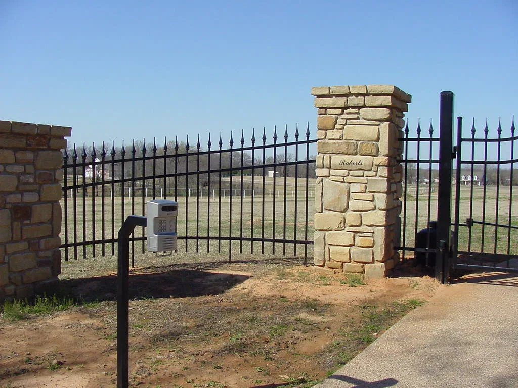Metal driveway gate installed between two fence sections