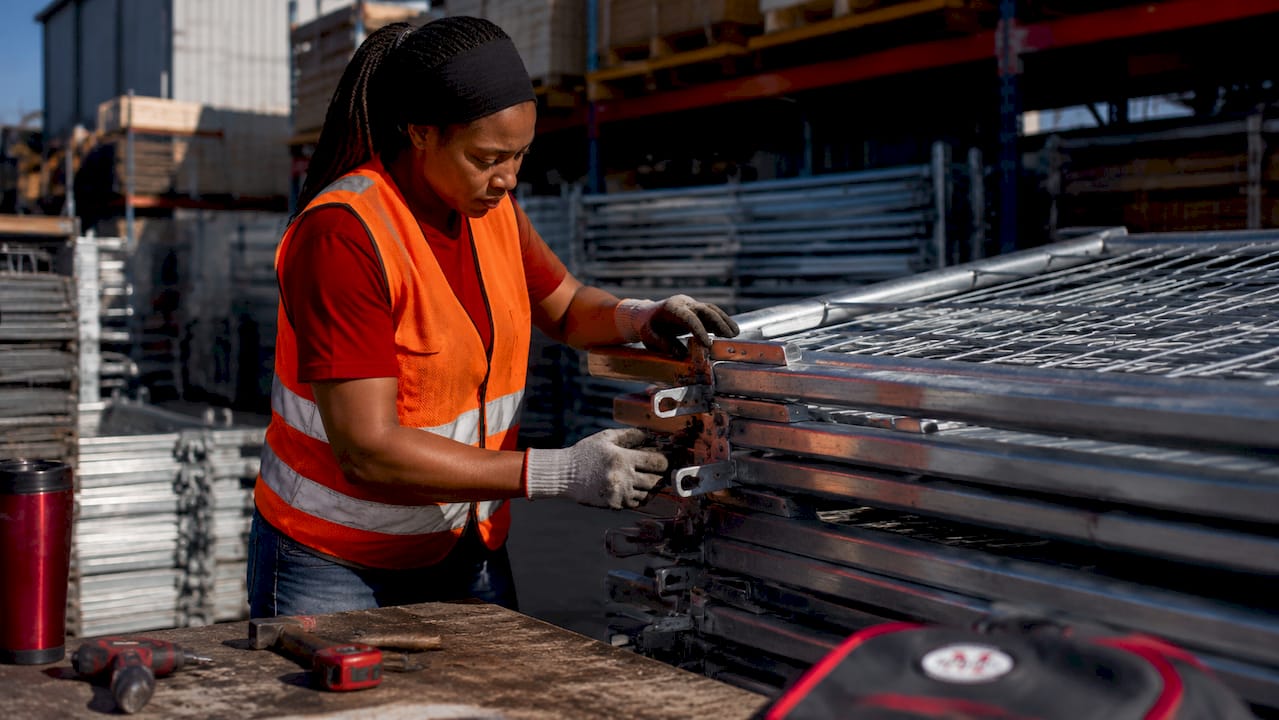 Warehouse worker handling galvanized steel fencing panels