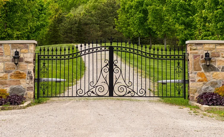 Ornamental driveway gate between masonry columns at a residential entrance