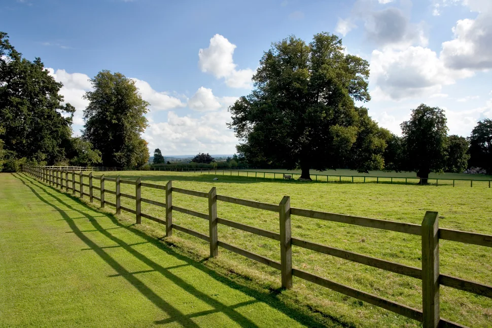 Black rail estate fencing running along a landscaped boundary