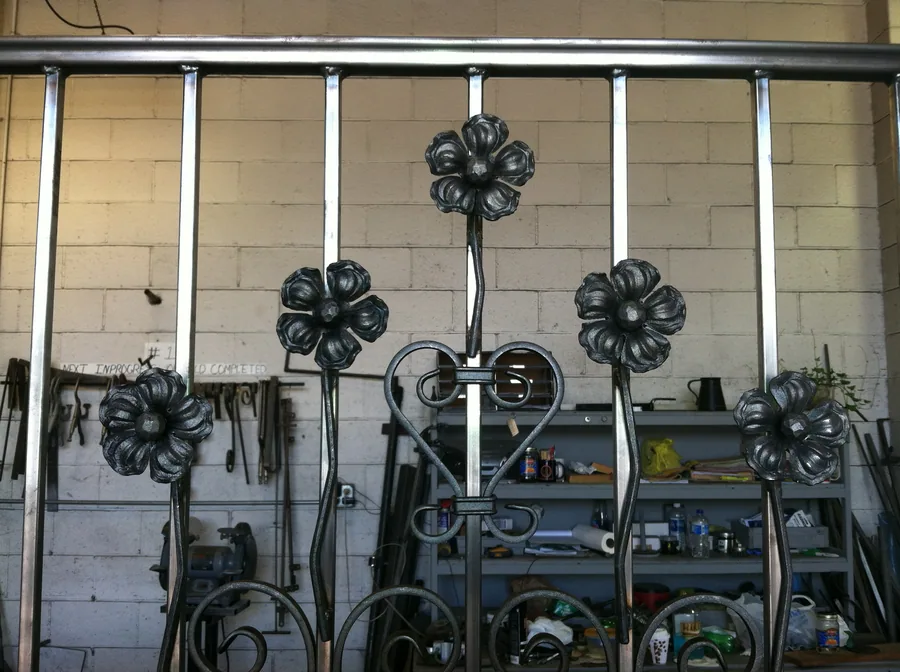 Ornamental iron scrollwork and gate components in the Modern Fence fabrication shop
