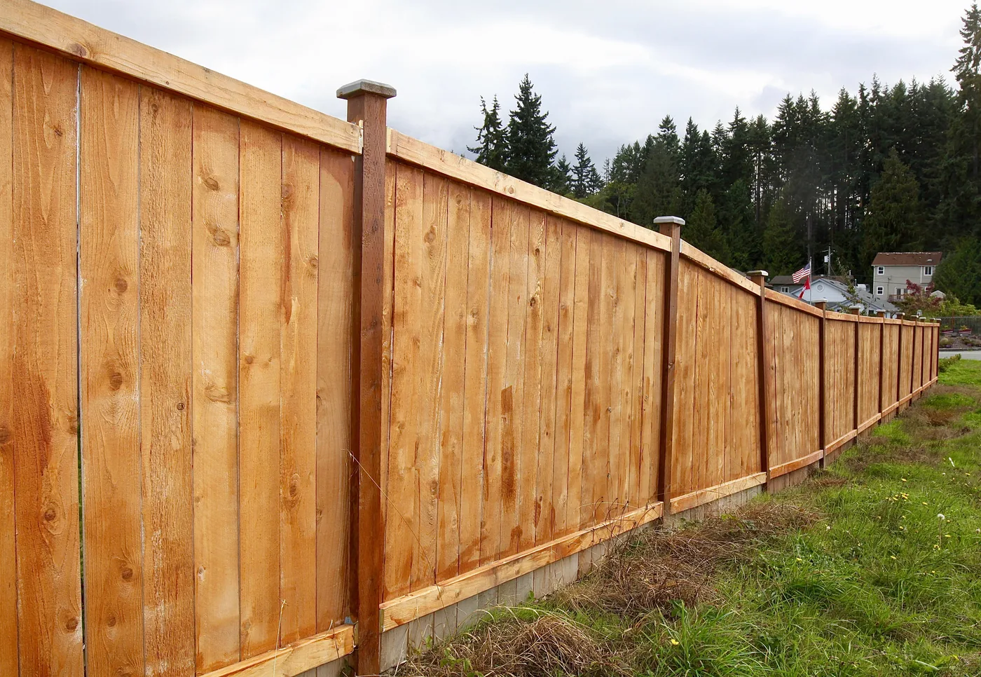 Completed solid-board cedar privacy fence running the length of a yard